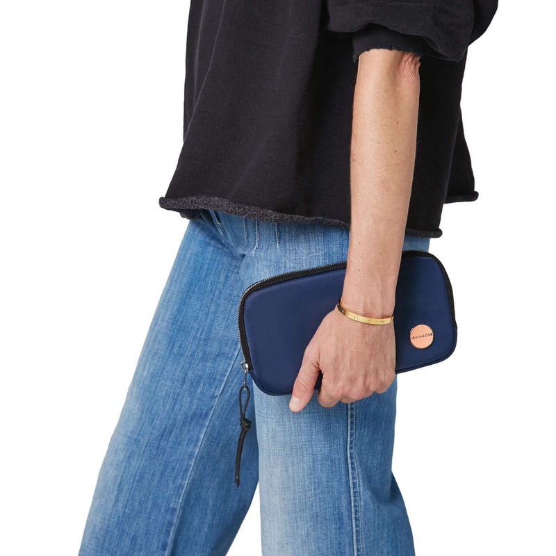 shortyLOVE jetty clutch/wallet in navy; hand held by model in black sweatshirt and jeans against white background.