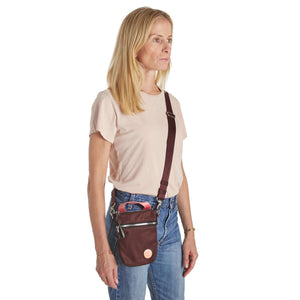 shortyLOVE shorthand small crossbody bag in burgundy; on model in peach t-shirt and jeans against white background.