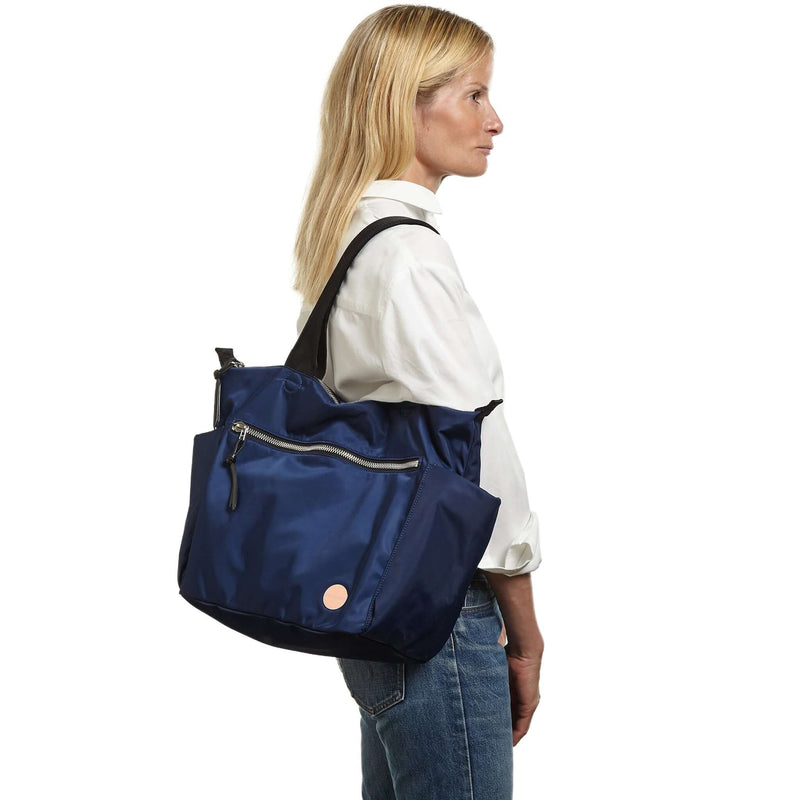shortyLOVE tillie tote bag in navy; on model in white button down shirt and jeans against white background.