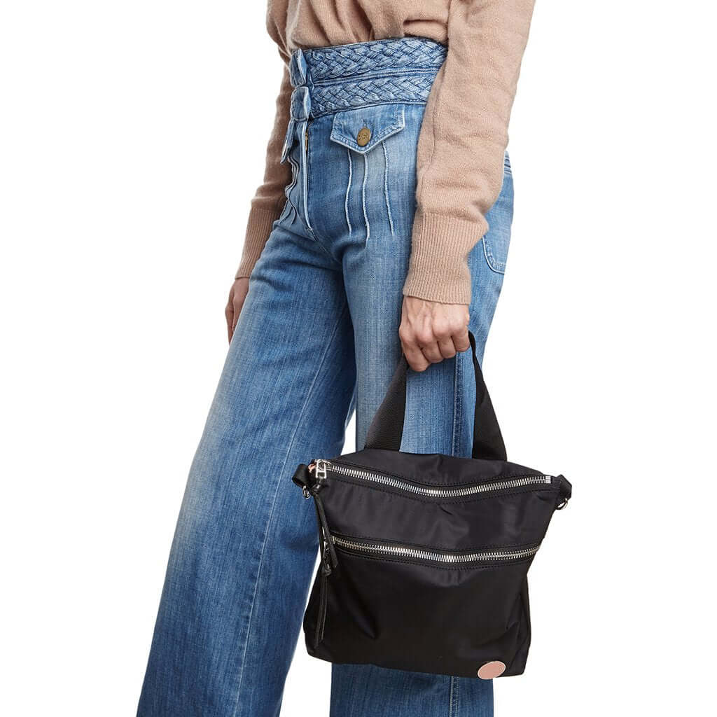 shortyLOVE amuse medium sized crossbody bag in black; on model in tan v-neck long sleeve sweater and jeans against white background.