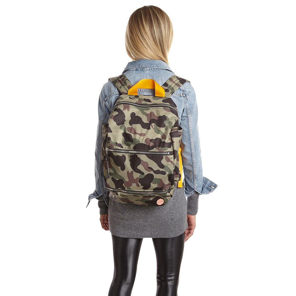 shortyLOVE boxer backpack bag in green camo; on model in blue jean jacket and black leggings against white background.